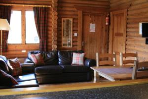 a living room with a leather couch and a table at Highgarry Lodges in Invergarry