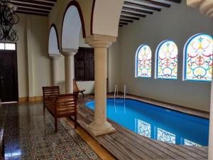 Hotel Catedral Valladolid Yucatan في فالادوليد: غرفة مع حمام سباحة مع نوافذ زجاجية ملطخة