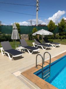 una piscina con tumbonas y sombrilla en Villa Selin, en Ovacık