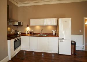 uma cozinha com armários brancos e um frigorífico branco em Host & Stay - Havelock Place Apartment em Whitby