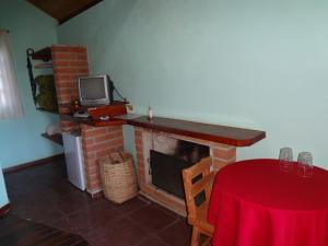 a living room with a fireplace with a table and a tv at Pousada Recanto da Vitória in Gonçalves