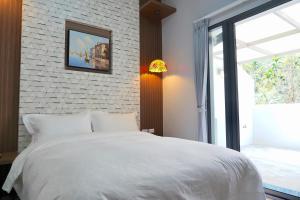 1 dormitorio con cama blanca y pared de ladrillo en MTNY Hotel, en Zhushan