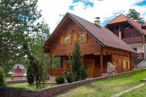 een blokhut met een veranda en een huis bij Rajska koliba in Kaludjerske Bare