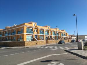 duży pomarańczowy budynek po stronie ulicy w obiekcie Pent house ocean view w mieście Cotillo