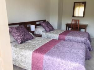 a bedroom with two beds with purple and white blankets at Hotel Meve Mar in Somo