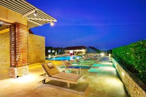 eine Terrasse mit Liegestühlen und einem Pool in der Nacht in der Unterkunft Intimate Hotel Pattaya - SHA Extra Plus in Pattaya