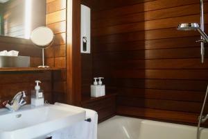 a bathroom with a sink and a tub and a mirror at Schwarzwald-Ferienwohnung mit Panorama und Pool in Sasbachwalden