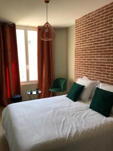 1 dormitorio con cama blanca y pared de ladrillo en Villa st Louis, en Cabourg