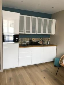 cocina blanca con armarios blancos y suelo de madera en Villa st Louis, en Cabourg