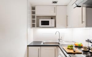 una cucina bianca con lavandino e forno a microonde di Classic Two-Bedroom Apartment Pimlico a Londra