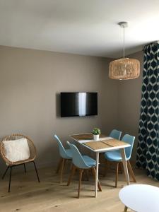 Un comedor con mesa y sillas y un televisor. en Villa st Louis, en Cabourg