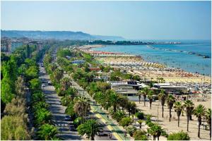 a beach with palm trees and crowds of people at Casavacanze estate 1 in San Benedetto del Tronto
