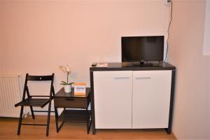 una TV in cima a un mobile bianco con tavolo e sedia di Casa Rendez Vous a Constanţa