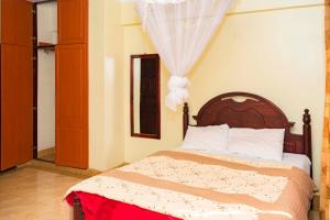 a bedroom with a bed with a wooden headboard at Florida Hotel Zaana Kampala in Kampala