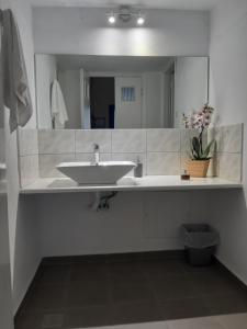 a white bathroom with a sink and a mirror at Villa Firostefani in Firostefani