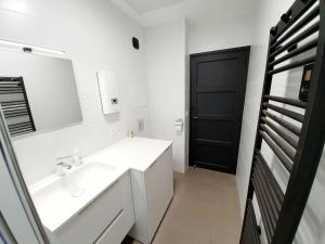 Baño blanco con lavabo y puerta negra en Le Pilo, en Saint-Malo