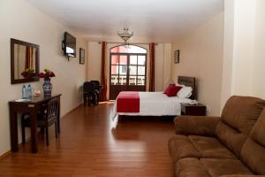 a living room with a bed and a couch at Hotel Plaza San Carlos in Xicotepec de Juárez