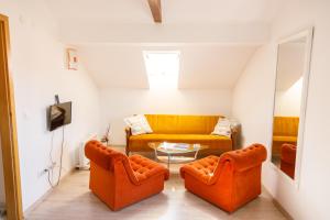 2 orangefarbene Stühle und ein Sofa im Wohnzimmer in der Unterkunft Apartmani Maraton in Vukovar