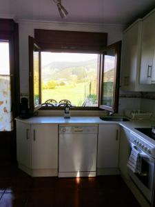 a kitchen with a sink and a large window at Chalet turístico La Jenduda in Ojedo