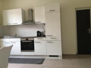 een keuken met witte kasten en een zwarte oven bij WALDSHUT SUITE IN ZENTRUM in Waldshut-Tiengen