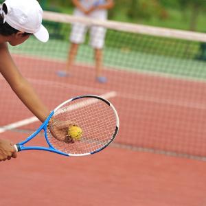 una persona sosteniendo una pelota de tenis con raqueta en Royal Beach Hôtel en Ambatoloaka