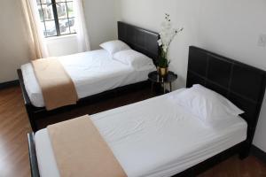 two beds with white sheets and a vase with flowers at Libra Hotel in Los Angeles