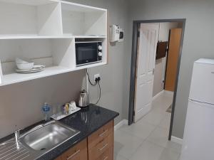 a kitchen with a sink and a microwave at Lux Rooms on 37 in Bloemfontein