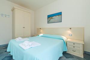 a bedroom with a white bed with towels on it at Biriola EcoResort Cala Gonone in Cala Gonone