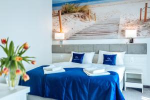a bedroom with a bed with blue sheets and a staircase at White Marina Apartamenty in Ustronie Morskie