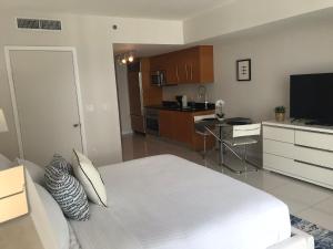 1 dormitorio con 1 cama blanca y cocina en Icon Residences by SS Vacation Rentals, en Miami