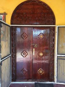 a large wooden door in a room with two windows at Wimbi Cottage in Nungwi