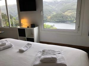1 dormitorio con 2 toallas en una cama y ventana grande en Casa Campacinas Casas Vacacional con vistas del rio en O Carballo