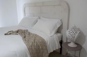 um quarto com uma cama branca e uma mesa lateral em CORALLI DEL PLEMMIRIO em Siracusa