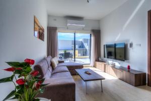 un soggiorno con un divano e una TV di Sunny Modern Apartments a Mellieħa