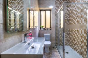 un bagno con lavandino, water e specchio di Sunny Modern Apartments a Mellieħa