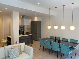 a kitchen and dining room with a table and blue chairs at ARRASATE SUITE Stylish, Super Central and New. in San Sebastián