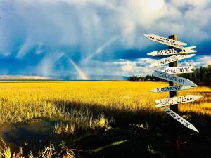 un cartello stradale davanti a un campo con un arcobaleno di Camp Caroli a Jukkasjärvi