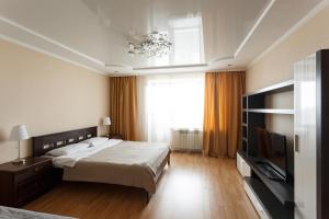 um quarto com uma cama, uma televisão e uma janela em Hochu Priehat na Cheluskintsev em Vologda