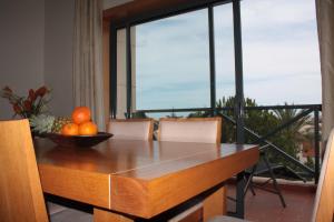 eine Schüssel Orangen auf einem Holztisch mit einem Fenster in der Unterkunft Apartamento com Piscina em Albufeira, Corcovada in Albufeira