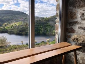 una ventana con un banco de madera con vistas al río en Casa Campacinas Casas Vacacional con vistas del rio en O Carballo