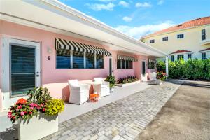a pink house with a patio with white furniture and flowers at The Gondolier Inn in Naples