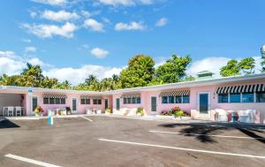 a pink building with tables and chairs in a parking lot at The Gondolier Inn in Naples