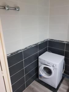 eine Waschmaschine im Bad mit schwarzen Fliesen in der Unterkunft Appartement vue Mer in Le Barcarès