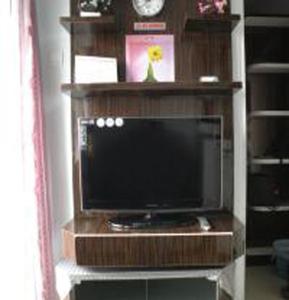 einen Flachbild-TV in einem hölzernen Entertainment-Center in der Unterkunft Apartment Green Pramuka ~ OCR in Jakarta