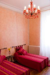 a bedroom with two beds and a chandelier at Appartements Maison Miro in Carcassonne