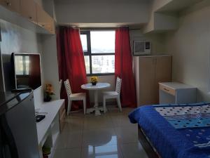 a bedroom with a bed and a table and a window at KC Studio 6 at Horizon 101 Cebu in Cebu City