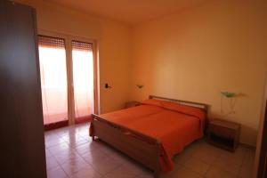 1 dormitorio con 1 cama con colcha de color naranja en Appartamenti San Foca, en San Foca