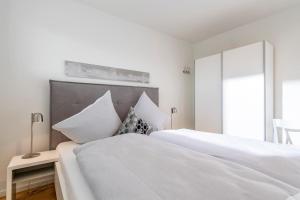 two beds in a bedroom with white walls at Harbour Side in Olpenitz