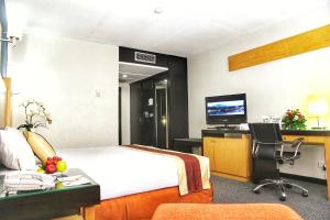 Habitación de hotel con cama, escritorio y TV. en Jayakarta Hotel Jakarta, en Yakarta