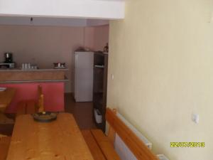a kitchen with a wooden table and a kitchen with a refrigerator at Panayotovi Guest House in Byala